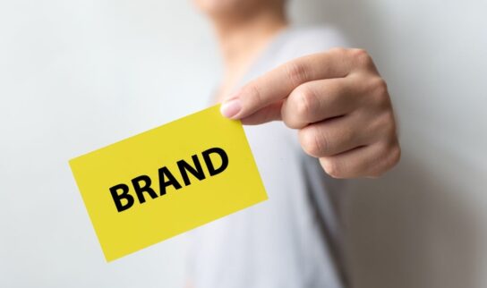 Man holding yellow card and word BRAND. Brand building for success concept Man holding yellow card and word BRAND. Brand building for success concept